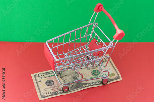 A shopping basket filled with medicines stands on a banknote on a red-green background. The concept of inflation and purchasing power.