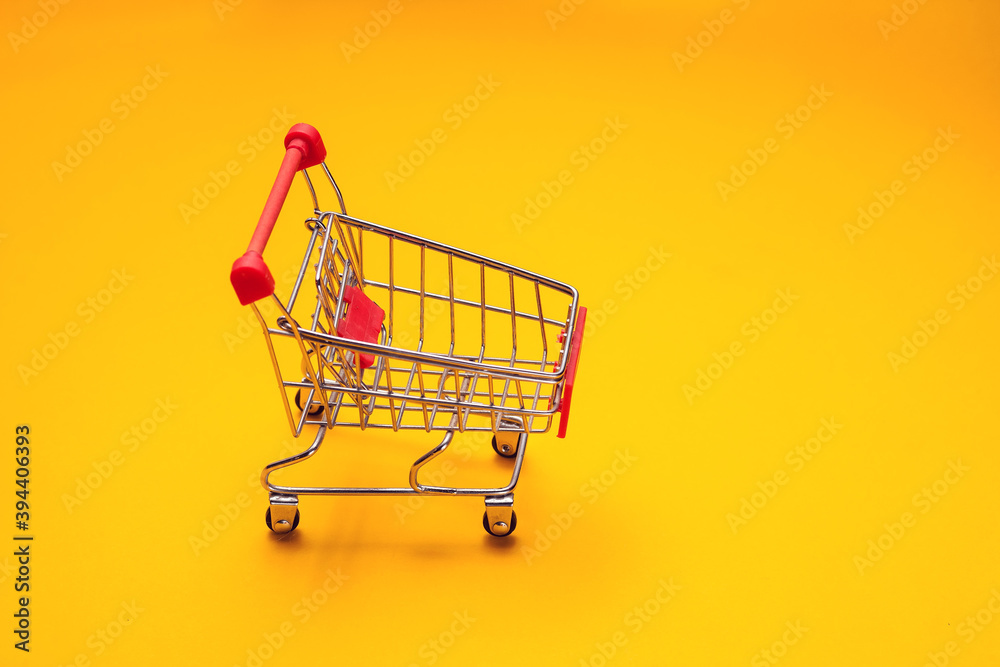 Trolley on yellow background. Shopping concept