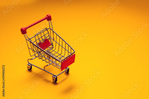 Trolley on yellow background. Shopping concept