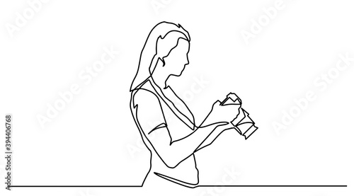Young tourist woman photographer with a camera takes pictures. One line drawing isolated vector object by hand on a white background. Continuous single drawn one line operator with camera
