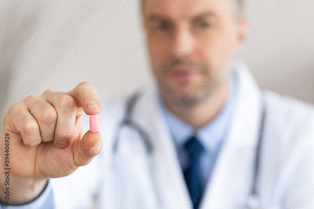 Experienced doctor showing pill to camera, selective focus Experienced doctor showing pill to camera, selective focus
