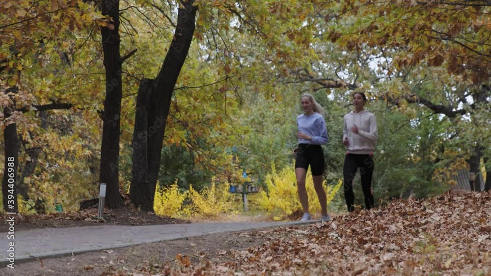 Two athletic fit women running together in autumn park Two athletic fit women running together in autumn park