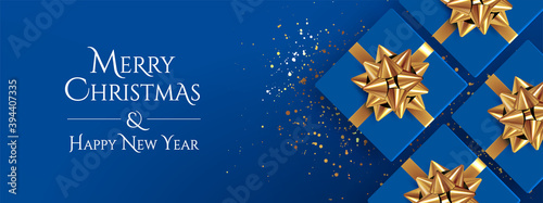 Christmas background. Classic blue christmas banner design with realistic top view gift boxes with golden bows and glitter confetti and Merry Christmas and Happy New Year lettering. Vector