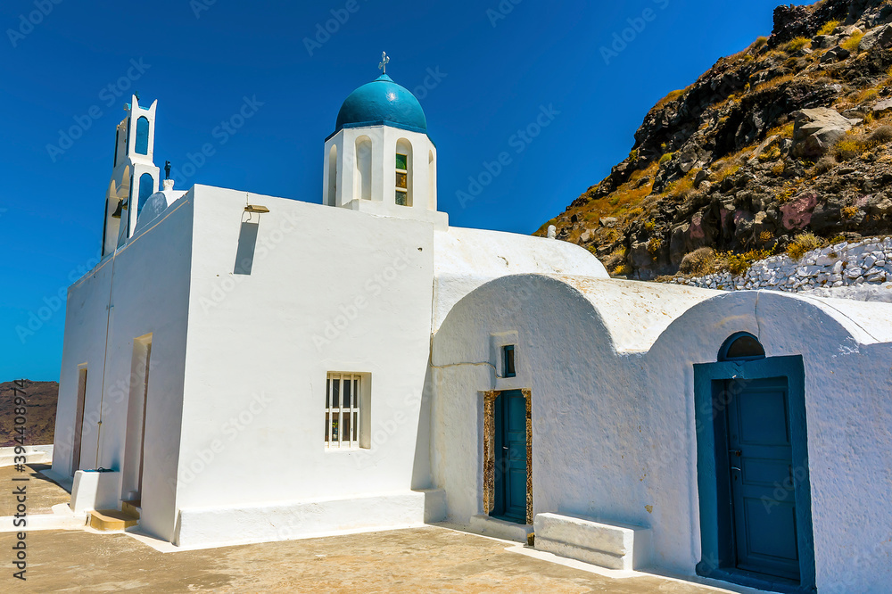 A view towards a traditional church on the side of Skaros Rock, Santorini in summertime