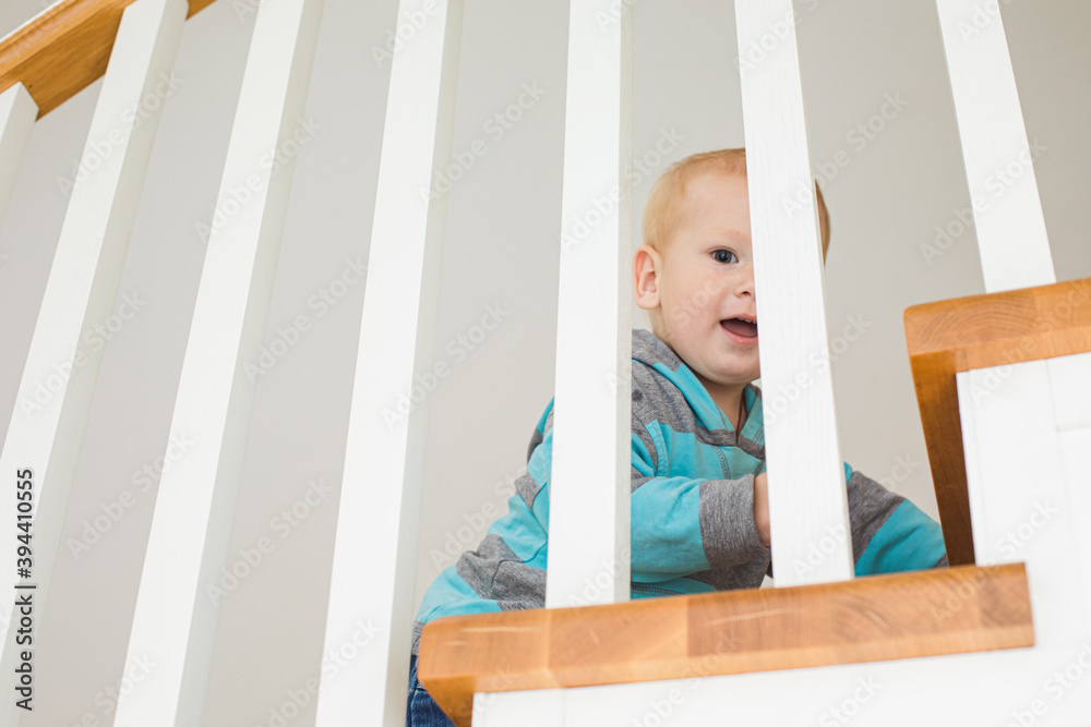 Cheerful boy on wooden stairs playing hide and seek Cheerful boy on wooden stairs playing hide and seek
