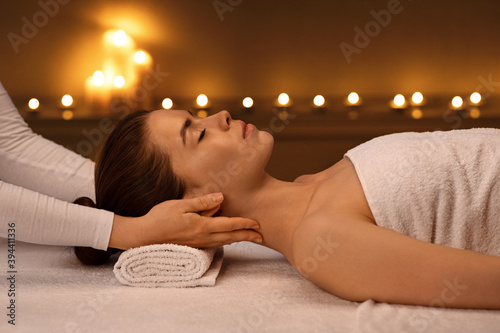 Unrecognizable therapist massaging sleeping woman neck, side view