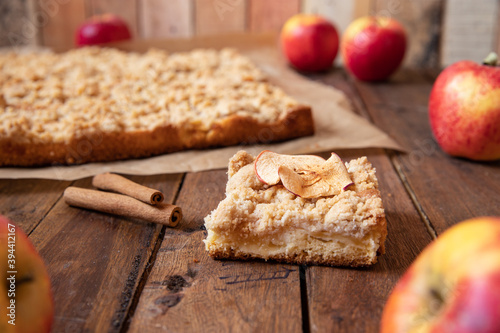 Kuchen mit Äpfeln als Füllung und Streusel auf einem braunen Tisch aus Holz in der Küche