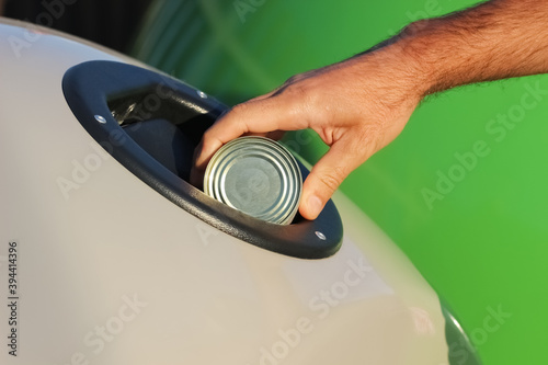 A person sorts the waste and puts an empty tin can in a container for receiving metal garbage.Concept of recycling and ecology.Caring for the environment