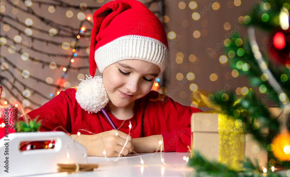 Boy in a red Christmas hat writes a letter to Santa Claus Boy in a red Christmas hat writes a letter to Santa Claus