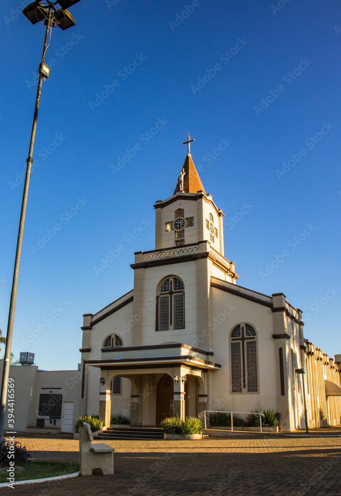 Fototapeta premium Main square and Catholic church of Guapiaçu, a charming town in the countryside of São Paulo, Brazil, showcasing local architecture and a peaceful atmosphere on a sunny day.