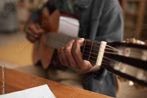 Close up of unrecognizable African-American man playing guitar while enjoying music at home, copy space