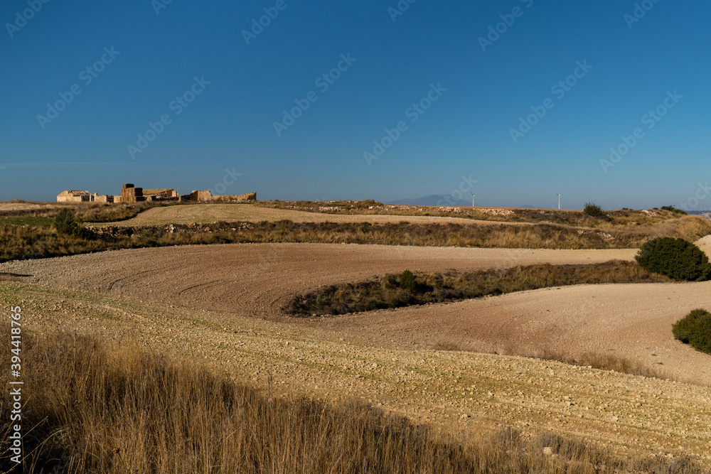 Recently sown fields with semi-destroyed sheepfolds and the peak of Moncayo in the background