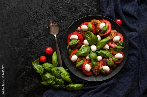 Italian Caprese salad with sliced tomatoes, mozzarella cheese, fried steaks, Basil, olive oil. Rustic style. The view from the top. Copy space.