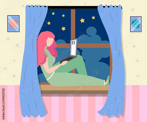 A woman works at a laptop while sitting on the windowsill at home. Freelance concept, quarantine due to covid-19