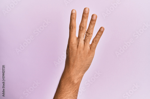 Arm and hand of caucasian young man over pink isolated background counting number 4 showing four fingers