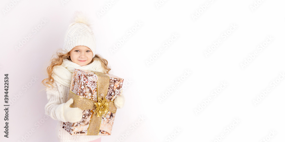 baby girl holding gift in warm hat and sweater on white isolated background, place for text, banner