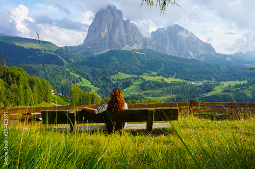Chica sentada en un banco con vistas de las montañas de los Alpes italianos. Dolomitas, Italia photo