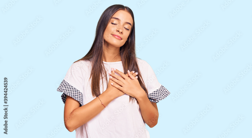 Young hispanic woman wearing casual clothes smiling with hands on chest with closed eyes and grateful gesture on face. health concept. Young hispanic woman wearing casual clothes smiling with hands on chest with closed eyes and grateful gesture on face. health concept.
