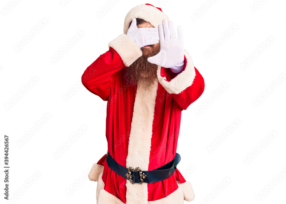 Handsome young red head man with long beard wearing santa claus costume covering eyes with hands and doing stop gesture with sad and fear expression. embarrassed and negative concept.