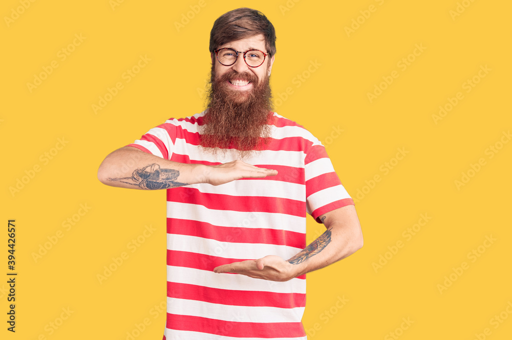 Handsome young red head man with long beard wearing casual clothes gesturing with hands showing big and large size sign, measure symbol. smiling looking at the camera. measuring concept. Handsome young red head man with long beard wearing casual clothes gesturing with hands showing big and large size sign, measure symbol. smiling looking at the camera. measuring concept.