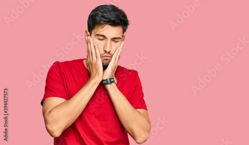 Young handsome man wearing casual red tshirt tired hands covering face  depression and sadness  upset and irritated for problem