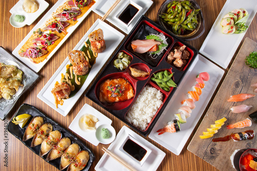 A top down view of a several varieties of Japanese izakaya style appetizers and entrees on a table.