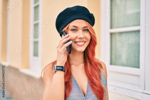 Young redhead girl wearing french style talking on the smartphone at the city.