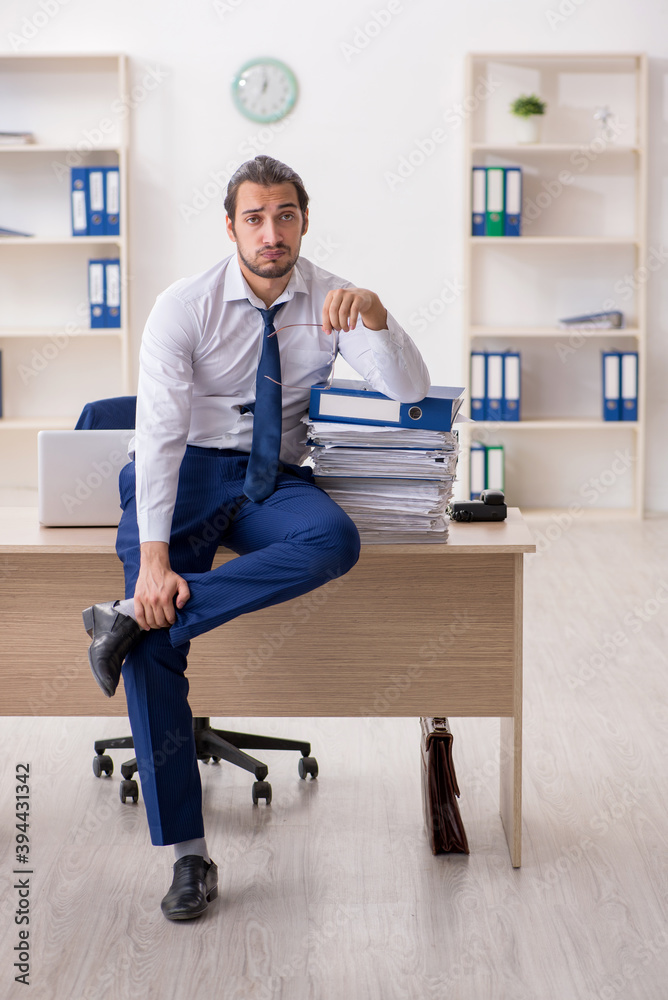 Young businessman unhappy with excessive work in the office Young businessman unhappy with excessive work in the office