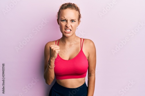 Beautiful caucasian woman wearing sportswear angry and mad raising fist frustrated and furious while shouting with anger. rage and aggressive concept. © Krakenimages.com