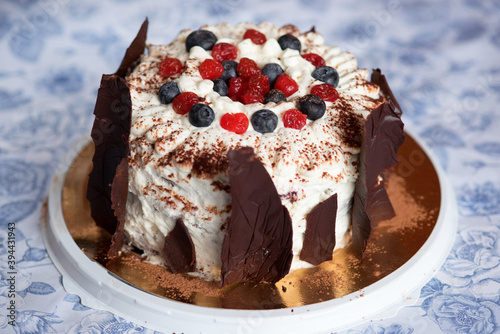 Chocolate cake on a plate with cream and berries.. cream cake with chocolate and berries