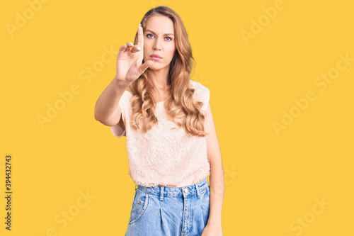 Young beautiful caucasian woman with blond hair wearing casual clothes pointing with finger up and angry expression, showing no gesture