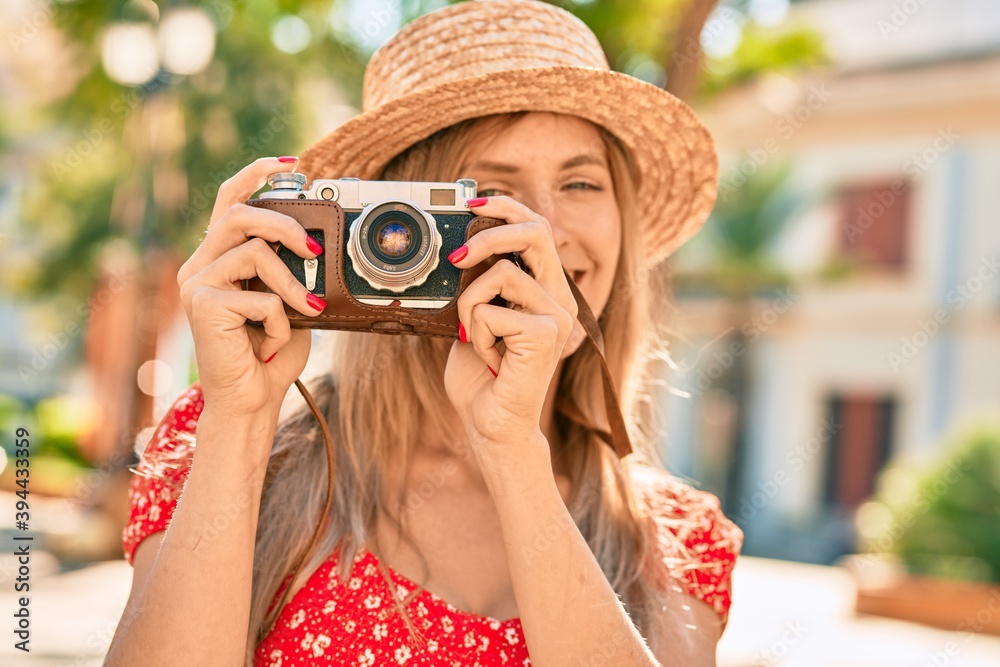 Young blonde tourist woman wearing summer style using vintage camera at the park