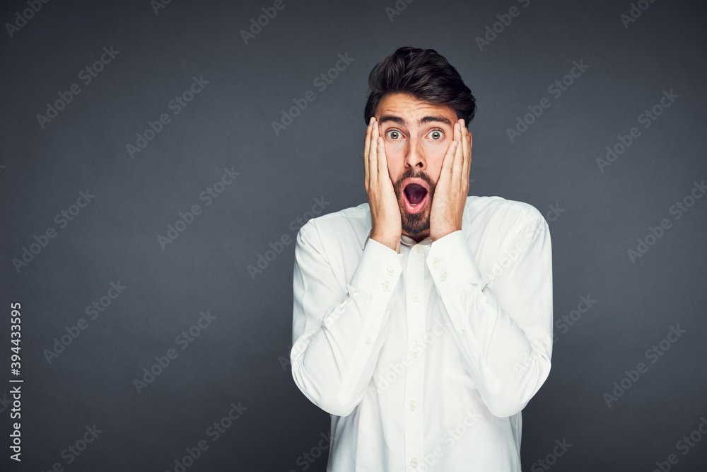 Shocked young man isolated against dark background Shocked young man isolated against dark background