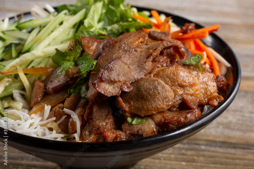 A view of a bowl of Vietnamese vermicelli noodles, also known as bún, featuring marinated beef. A view of a bowl of Vietnamese vermicelli noodles, also known as bún, featuring marinated beef.