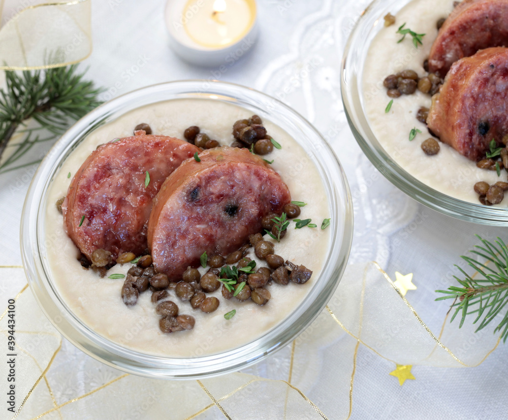 Fette di cotechino con crema di lenticchie servito su piatto. Decorazioni natalizie. Cibo italiano.