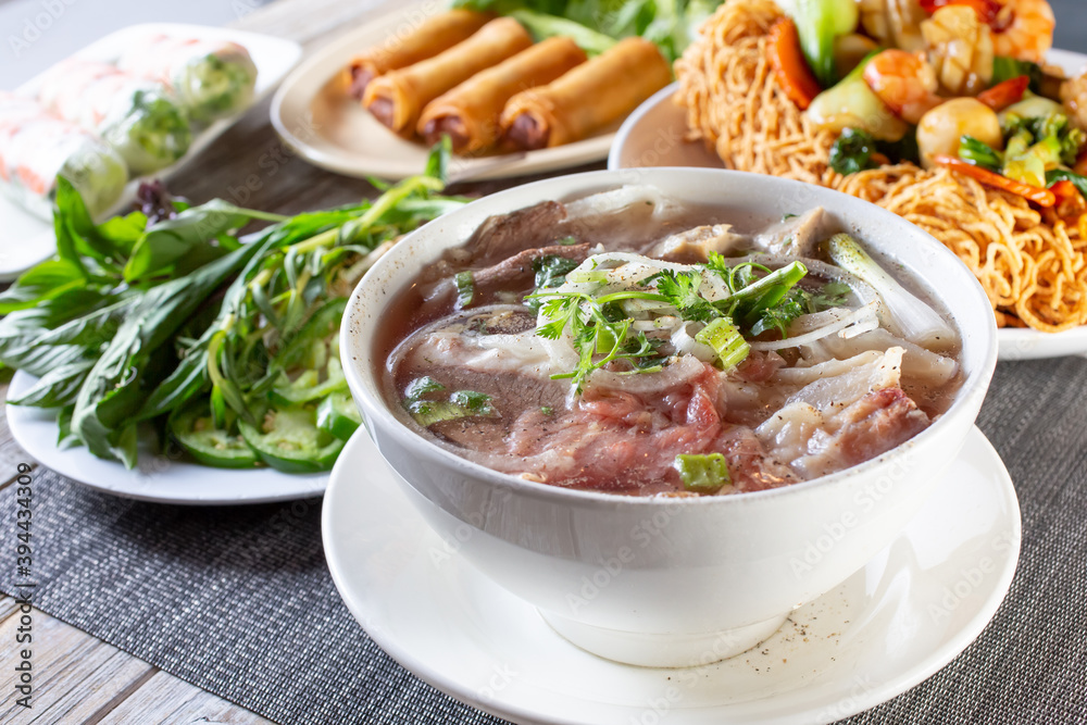 A view of a table full of a variety of Vietnamese dishes, featuring pho. A view of a table full of a variety of Vietnamese dishes, featuring pho.