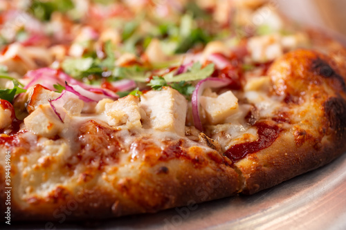 A closeup view of the chicken toppings and crust of a BBQ chicken pizza.