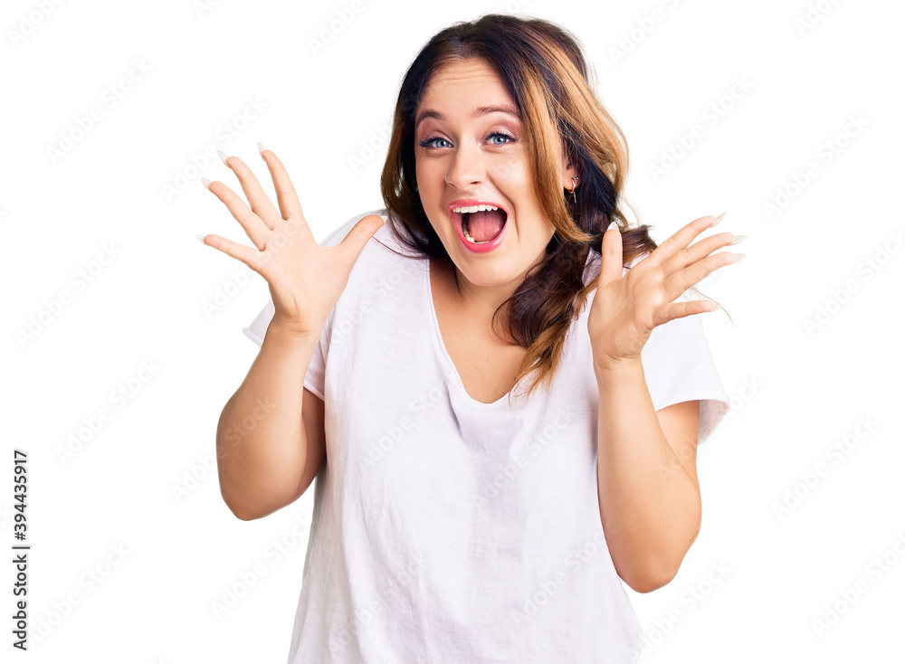 Young beautiful caucasian woman wearing casual white tshirt celebrating crazy and amazed for success with arms raised and open eyes screaming excited. winner concept Young beautiful caucasian woman wearing casual white tshirt celebrating crazy and amazed for success with arms raised and open eyes screaming excited. winner concept