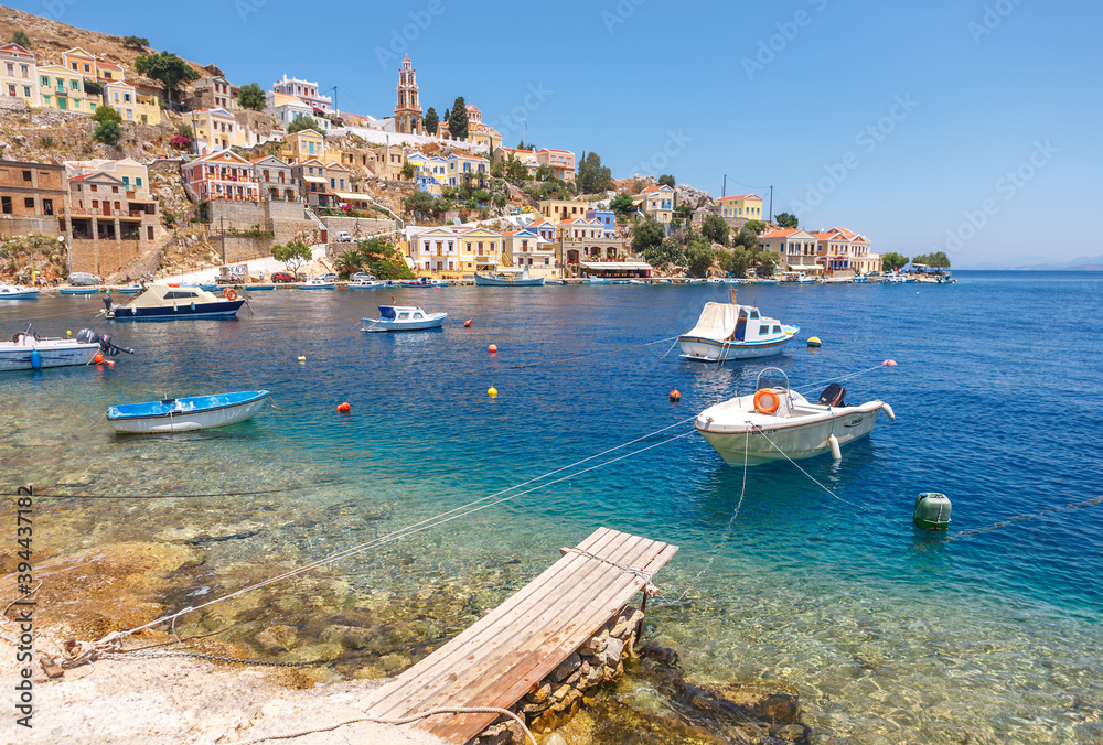 Fototapeta premium Simi-Greece-July 04, 2011: View of the Bay, beautiful colorful houses and fishing boats of Simi island, Greece