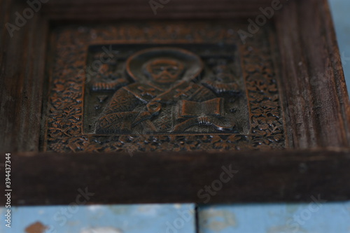 close-up religious image of metal in a frame on a wooden background