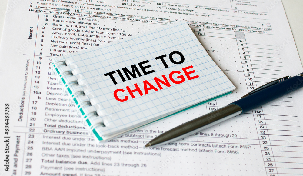 Notepad with text Time To Change lying on financial tables with a pen Notepad with text Time To Change lying on financial tables with a pen