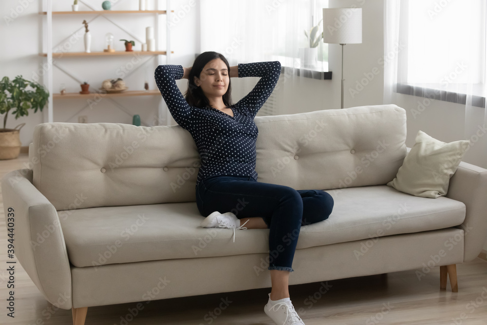 Satisfied Asian woman relaxing with closed eyes, stretching on couch at home, peaceful attractive female with hands behind head leaning back, resting on sofa in living room, enjoying lazy weekend