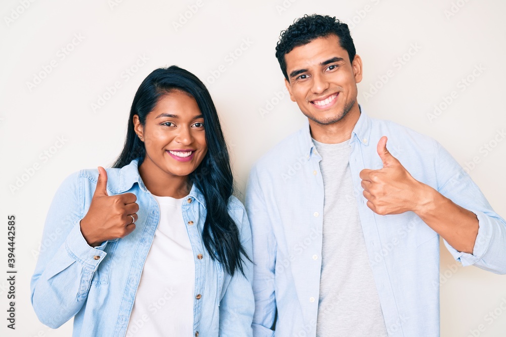 Beautiful latin young couple wearing casual clothes success sign doing positive gesture with hand, thumbs up smiling and happy. cheerful expression and winner gesture. Beautiful latin young couple wearing casual clothes success sign doing positive gesture with hand, thumbs up smiling and happy. cheerful expression and winner gesture.