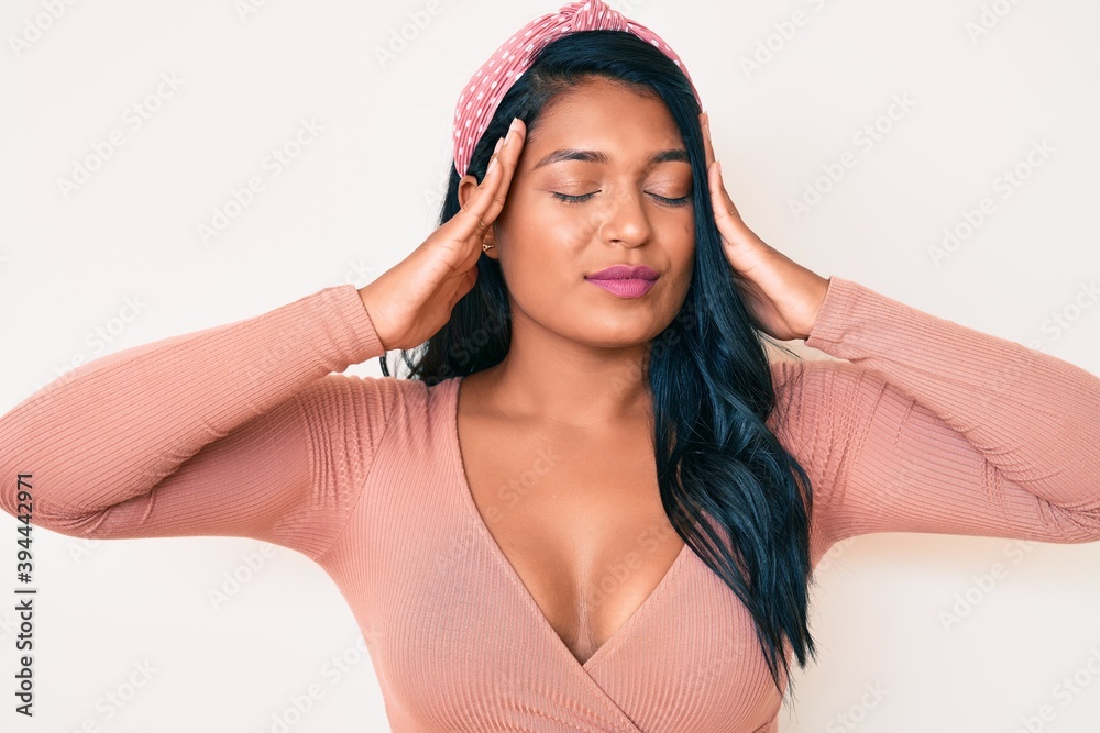 Beautiful latin young woman with long hair wearing casual style with hand on head, headache because stress. suffering migraine.