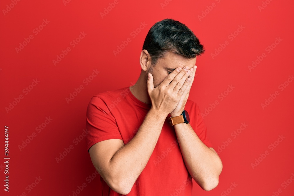 Handsome caucasian man wearing casual red tshirt with sad expression covering face with hands while crying. depression concept. Handsome caucasian man wearing casual red tshirt with sad expression covering face with hands while crying. depression concept.