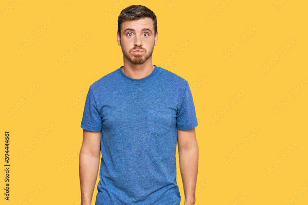 Handsome caucasian man wearing casual clothes puffing cheeks with funny face. mouth inflated with air, crazy expression.