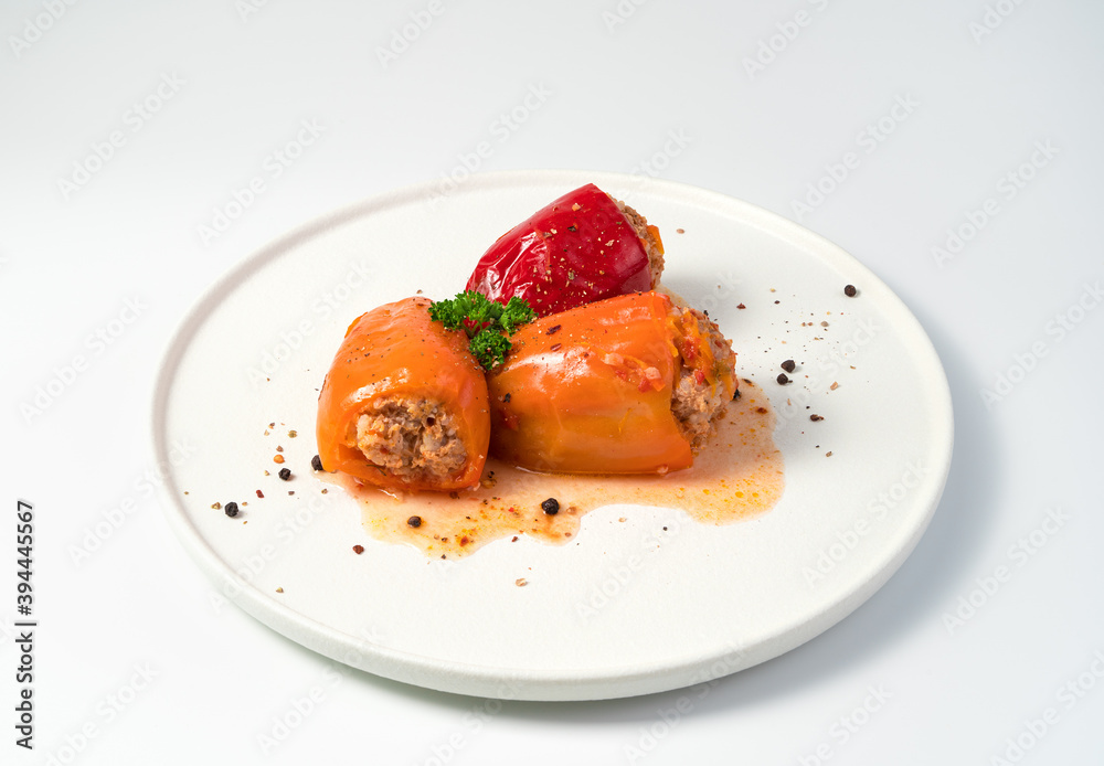 Dish with stewed bell pepper, herbs and seasonings on a white background. Side view, close-up. The concept of cooking. Dish with stewed bell pepper, herbs and seasonings on a white background. Side view, close-up. The concept of cooking.