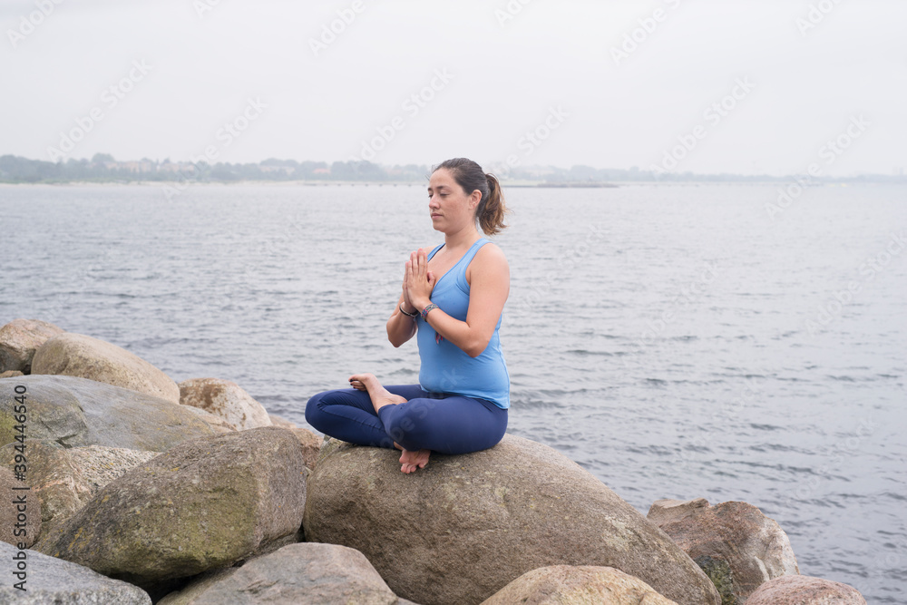 Woman meditating at sea, Sweden Woman meditating at sea, Sweden