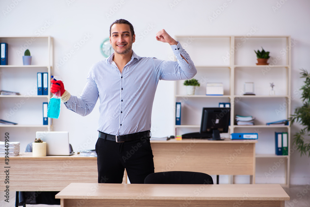 Young male employee cleaning office during pandemic