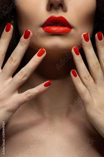 Beautiful young model with red lips and red manicure.